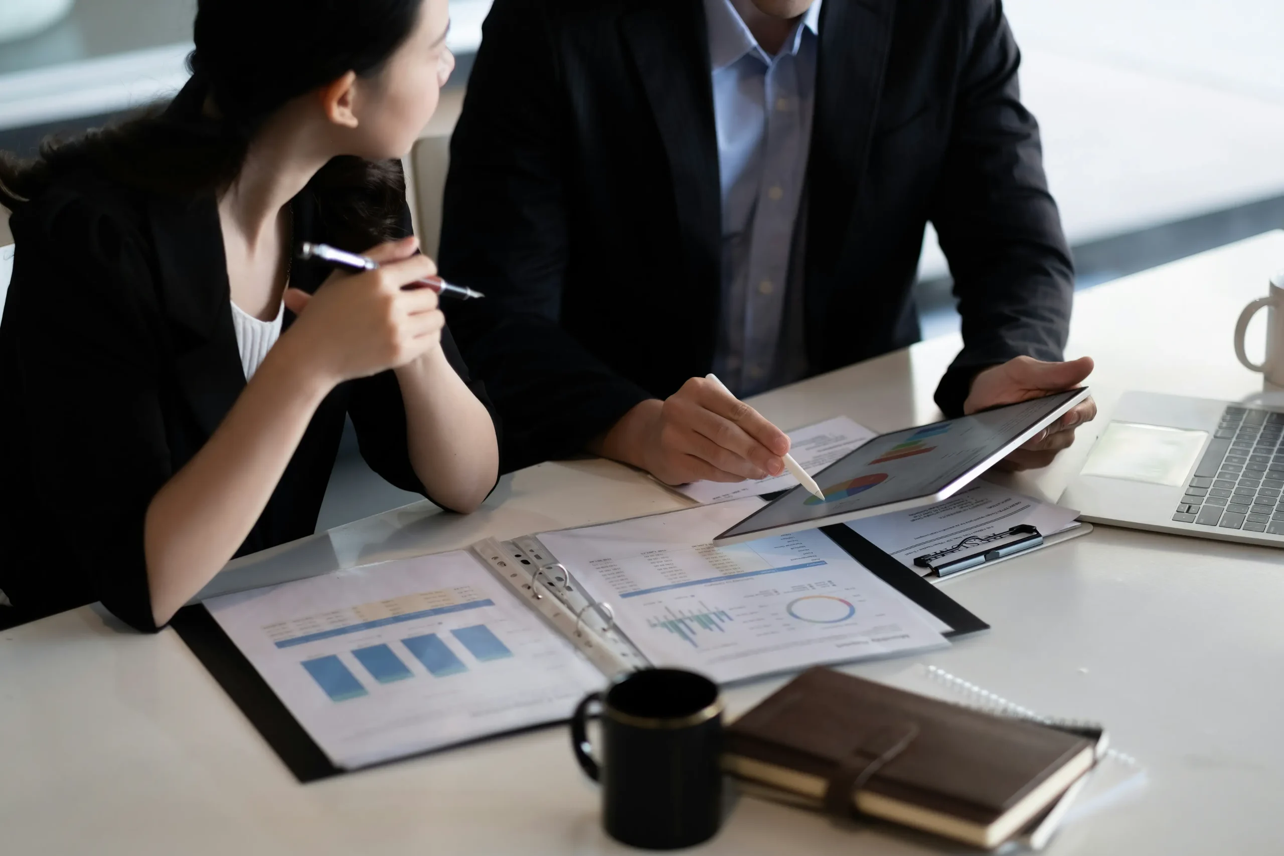 close-up-of-business-people-discussing-a-financial-plan-with-paperwork-and-digital-tablet